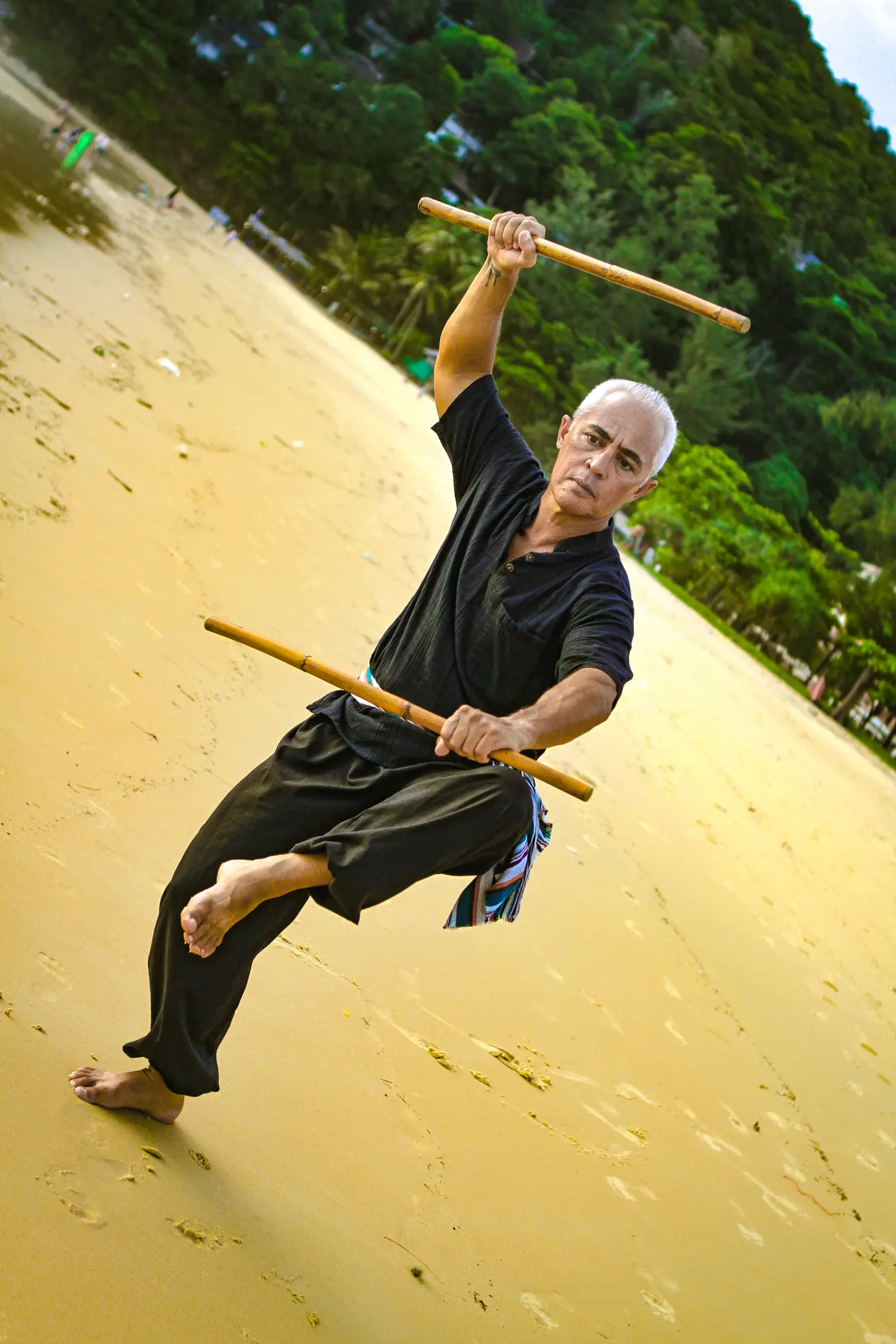 Karol Krauser performing Filipino Kali double stick fighting stance on Phuket beach Thailand