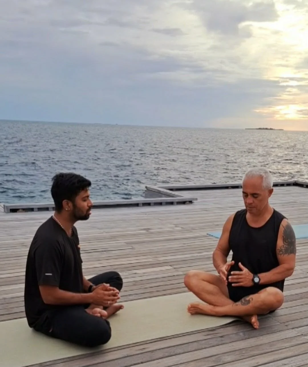 Karol Krauser leading private meditation and breathwork session on overwater deck at sunset in the Maldives
