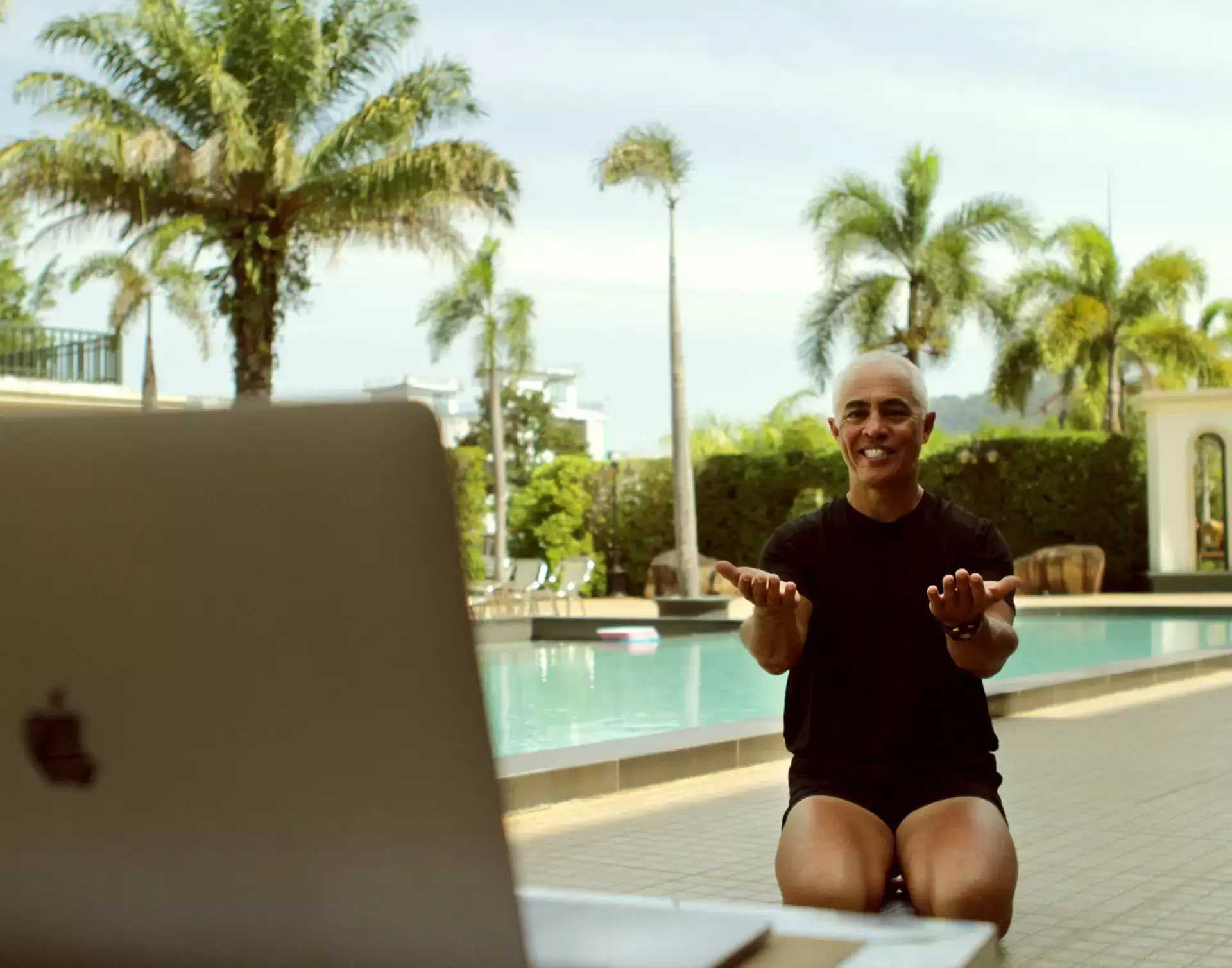 Karol Krauser conducting online personal training session poolside at tropical resort in Southeast Asia