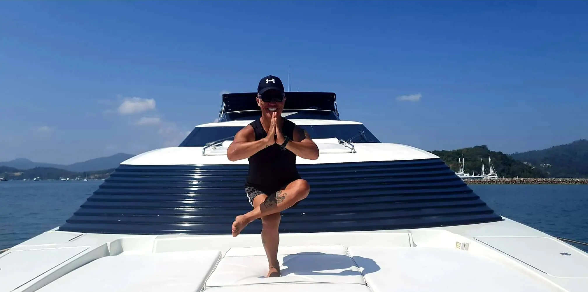 Karol Krauser practicing yoga tree pose on the bow of yacht Demarest in Phuket Thailand