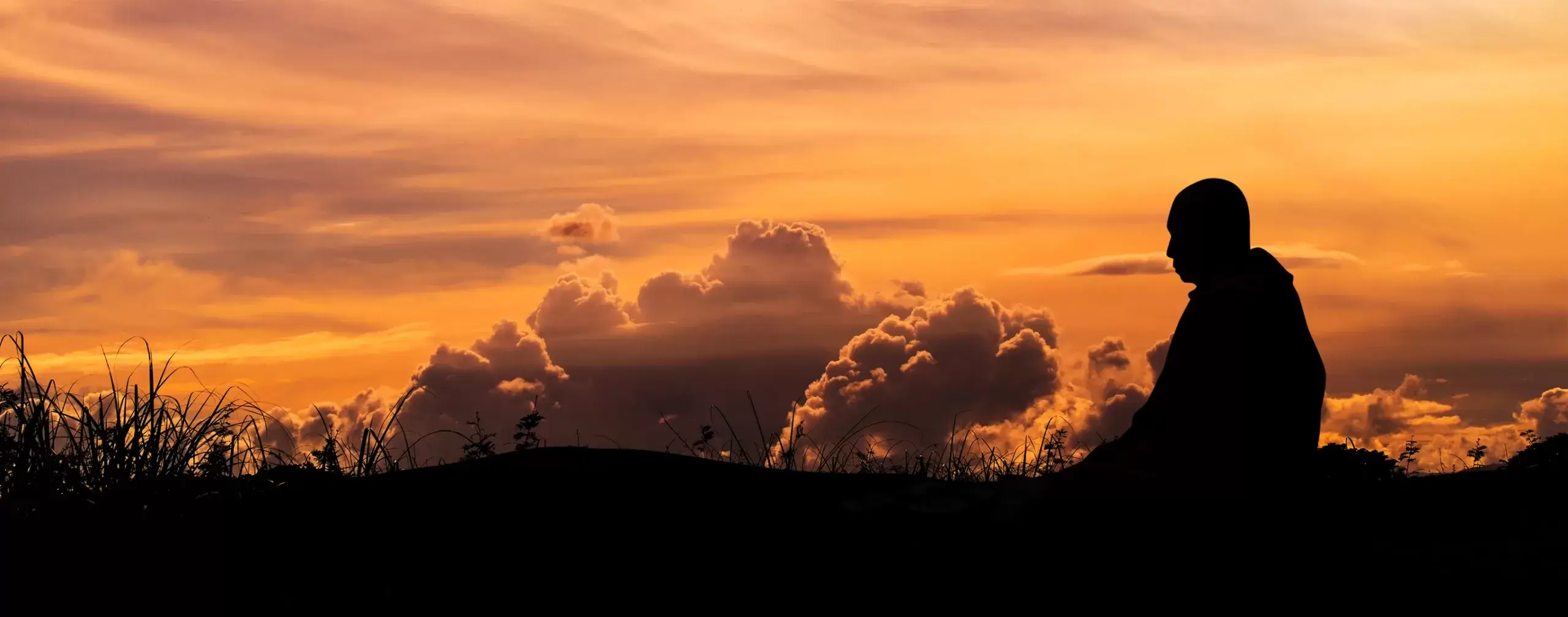 Meditation silhouette at sunset with dramatic clouds for mindfulness practice