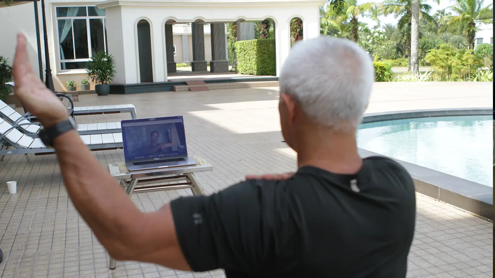 Client receiving online fitness coaching at outdoor villa pool showing flexibility of remote training locations